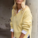 model wears a yellow knit jumper with blue jeans