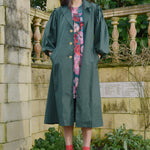 Model wears a green trench coat with a floral dress