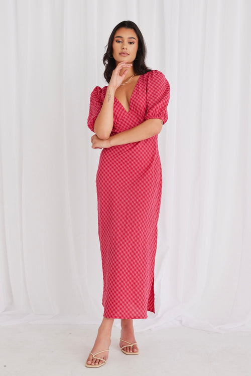 model wears a long gingham pink dress and heels