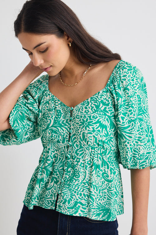 model wears a green floral blouse 