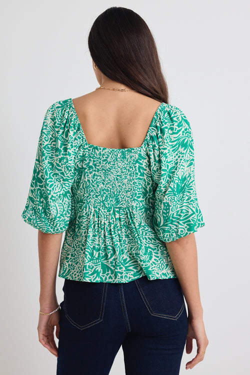 model wears a green floral blouse 