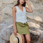 model wears linen vest and green linen mini skirt at the beach