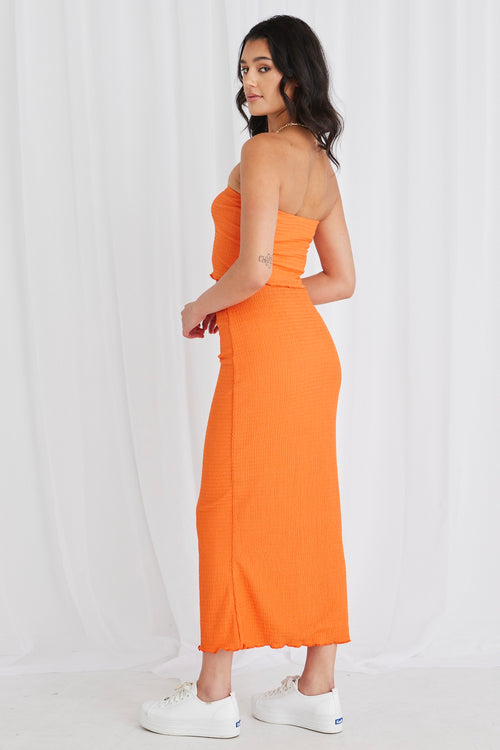 Model wearing orange bandeau top and maxi skirt set