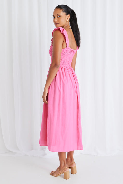 model wears long pink midi dress and tan heels. 