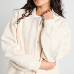 model wears a white bomber jacket with grey pants