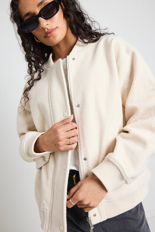 model wears a white bomber jacket with grey pants