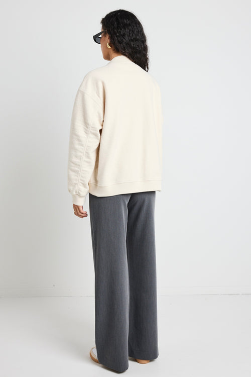 model wears a white bomber jacket with grey pants