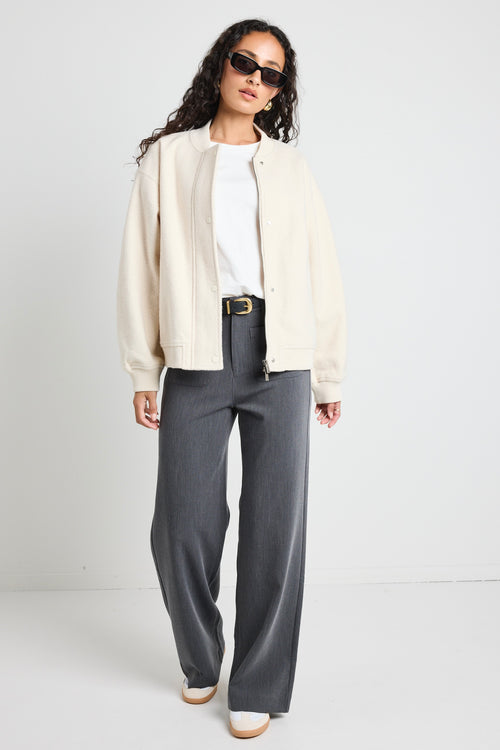 model wears a white bomber jacket with grey pants