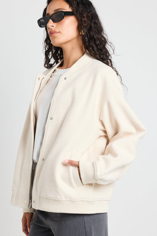 model wears a white bomber jacket with grey pants