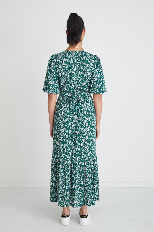 model posing in green floral maxi dress and white sneakers