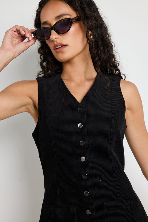 Model wears a black cord mini dress with silver buttons