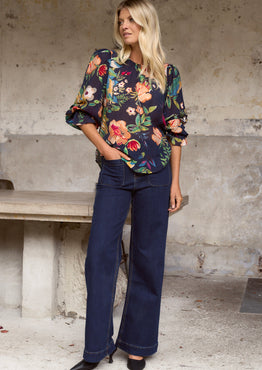 model wears a navy floral blouse with dark blue jeans
