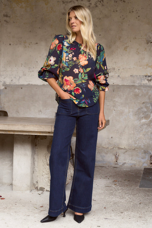 model wears a navy floral blouse with dark blue jeans