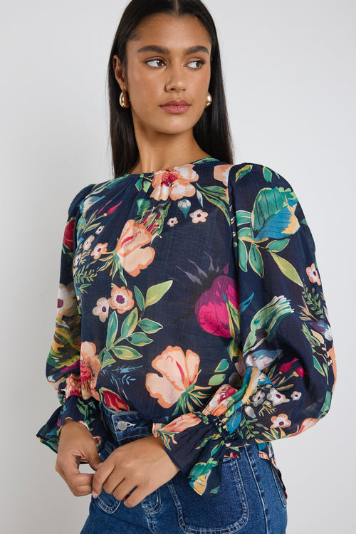 model wears a navy floral blouse with dark blue jeans