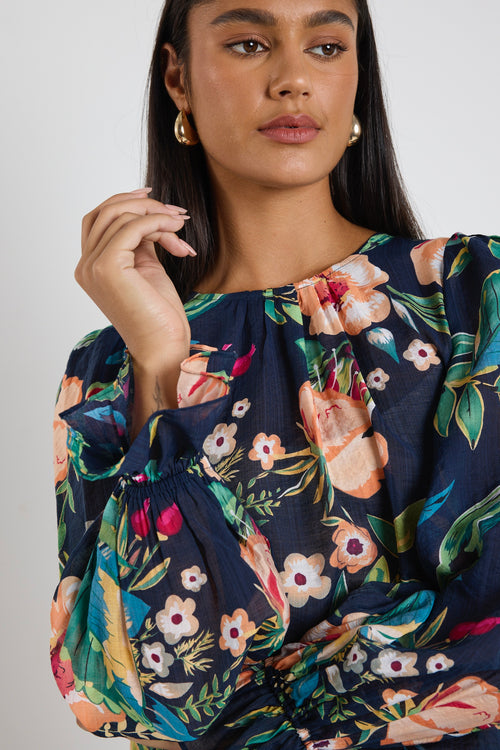 model wears a navy floral blouse with dark blue jeans