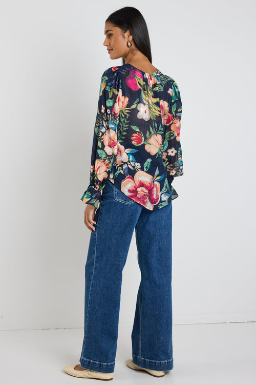model wears a navy floral blouse with dark blue jeans