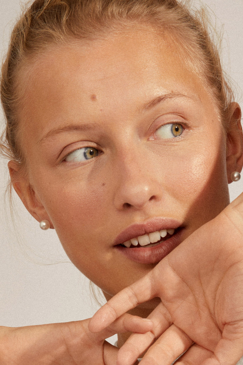 model wearing pearl stud earrings