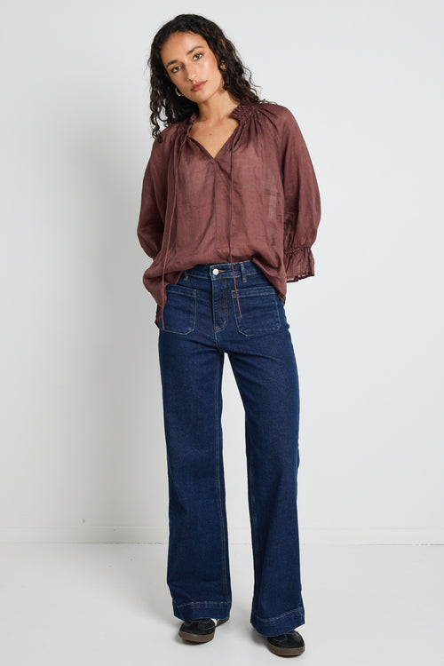 model wears a brown linen top with jeans