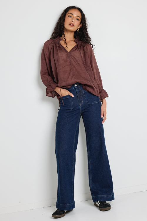 model wears a brown linen top with jeans