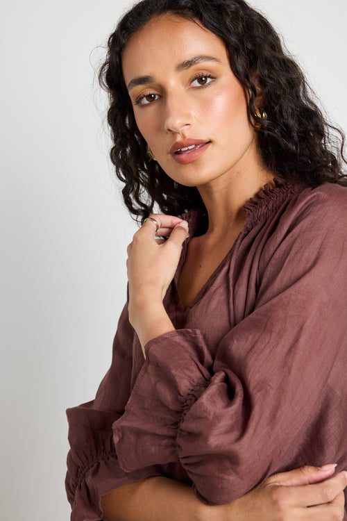 model wears a brown linen top with jeans