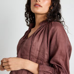 model wears a brown linen top with jeans