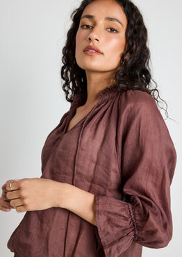 model wears a brown linen top with jeans