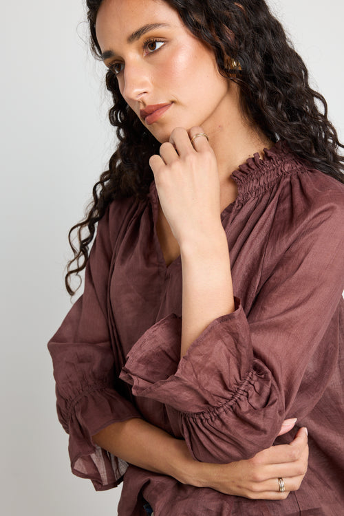 model wears a brown linen top with jeans