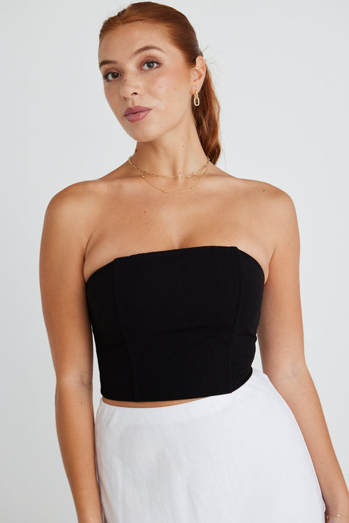 model wears a strapless black top with white midi skirt