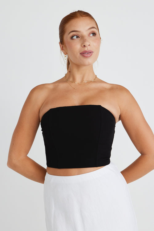 model wears a strapless black top with white midi skirt