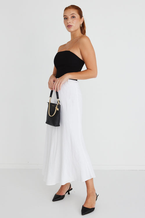 model wears a strapless black top with white midi skirt and black heels