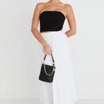 model wears a strapless black top with white midi skirt and black heels