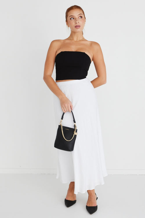 model wears a strapless black top with white midi skirt and black heels