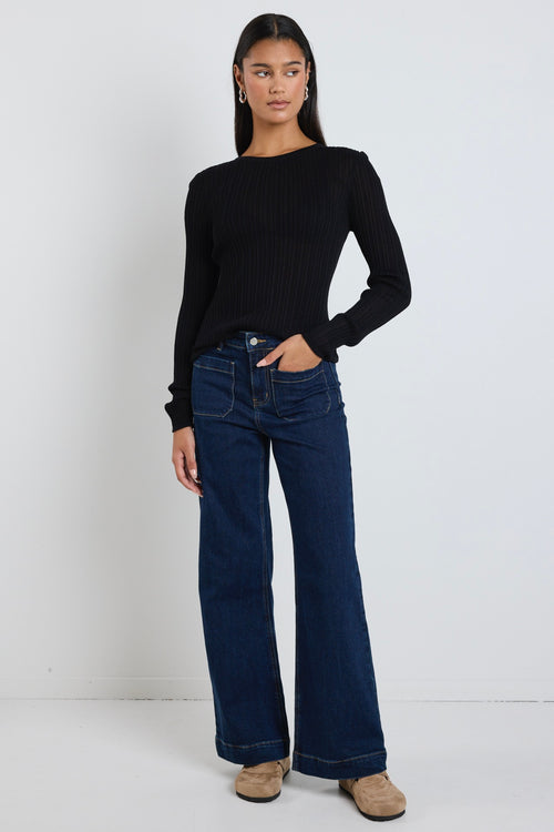 Model wears black long sleeve top with dark blue jeans