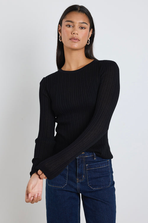 Model wears black long sleeve top with dark blue jeans