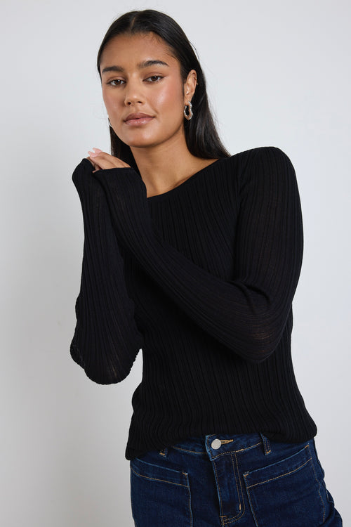 Model wears black long sleeve top with dark blue jeans