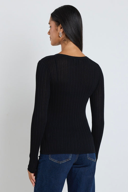 Model wears black long sleeve top with dark blue jeans