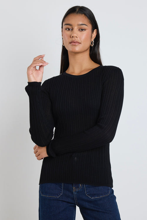 Model wears black long sleeve top with dark blue jeans