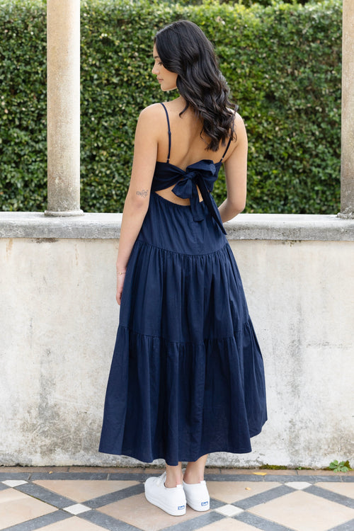 Model posing in navy maxi dress and white slides