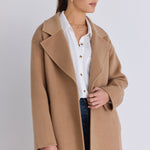 Model wears a brown beige coat with blue jeans