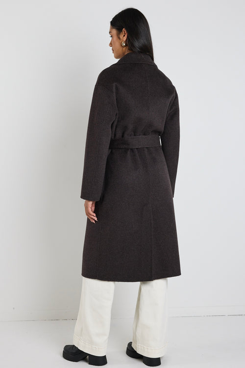 Woman wearing a chocolate brown longline coat over a black tank and cream wide-leg jeans, styled with black boots.