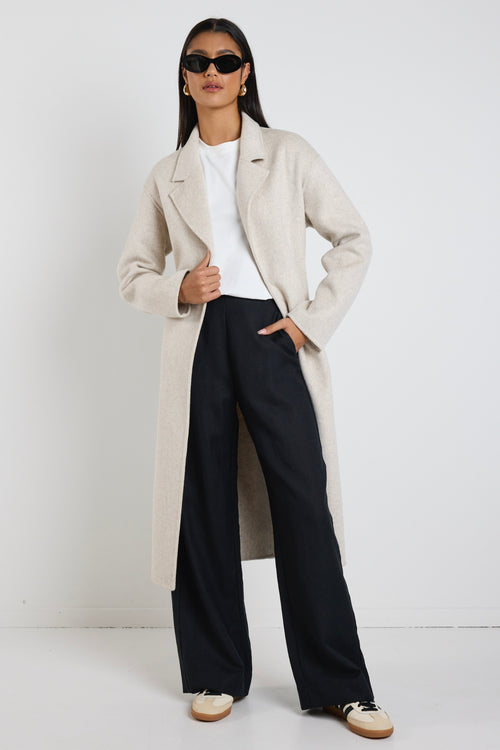 model wears a light grey coat with black pants