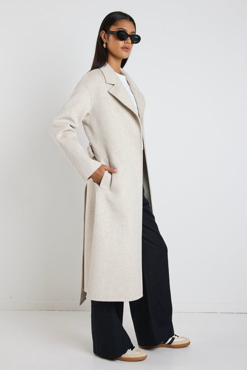 model wears a light grey coat with black pants