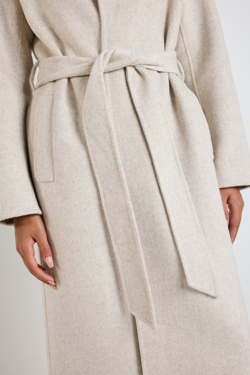 model wears a light grey coat with black pants