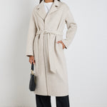 model wears a light grey coat with black pants