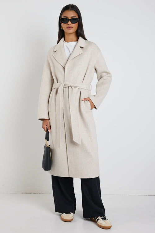 model wears a light grey coat with black pants
