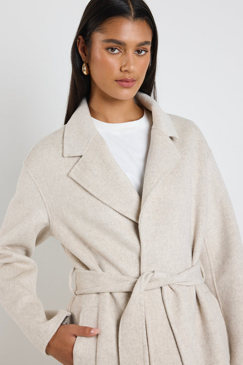 model wears a light grey coat with black pants
