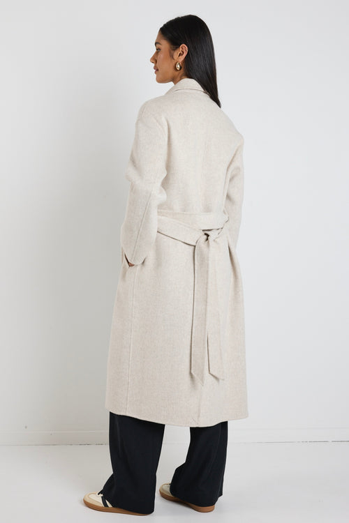 model wears a light grey coat with black pants