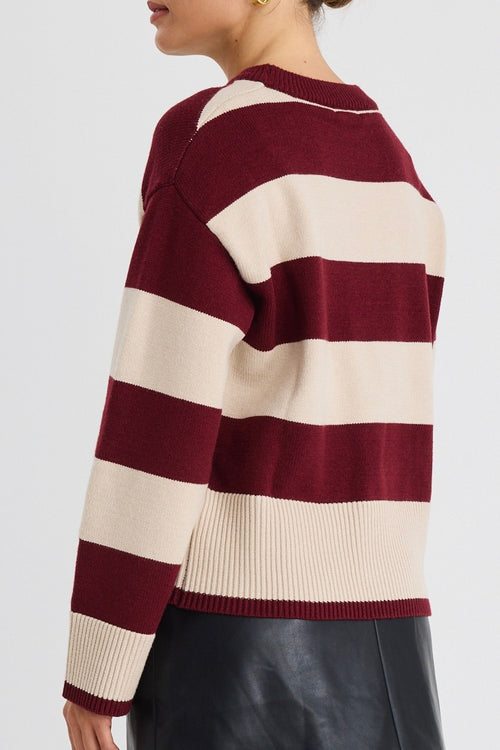 Woman wearing a burgundy and oatmeal striped jumper with long sleeves and a leather mini skirt.
