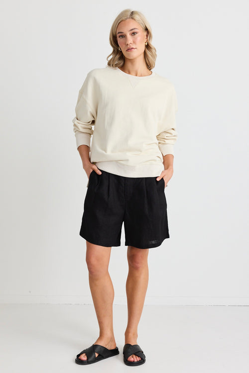 Model wears a cream sweatshirt and black shorts