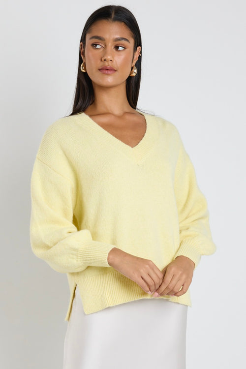model wears a yellow knit jumper with blue jeans